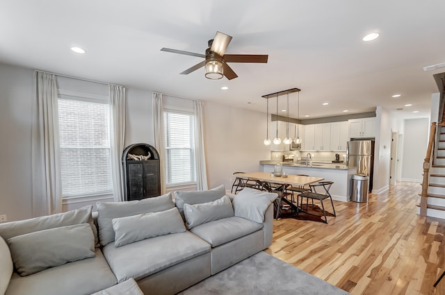 living room featuring sink, ceiling fan, and light wood-type flooring