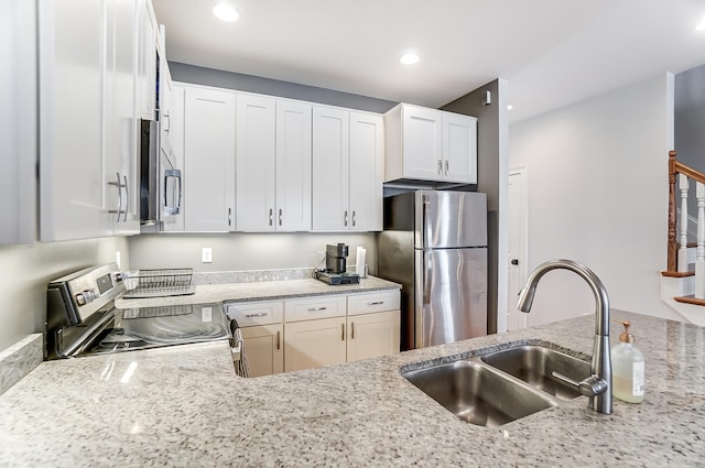 kitchen with stainless steel appliances, sink, white cabinets, and light stone counters