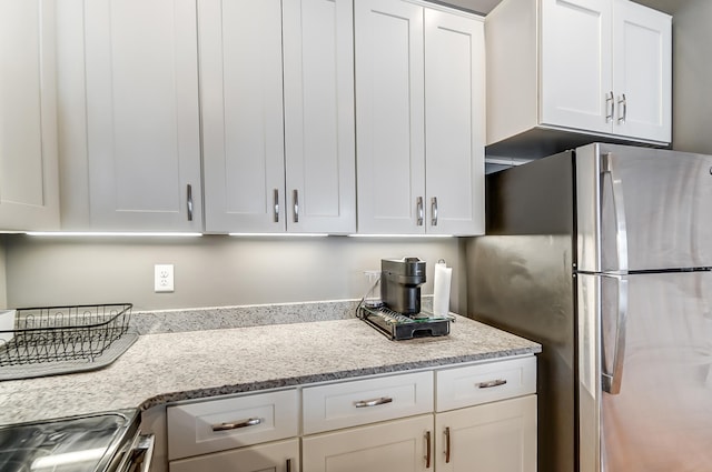 kitchen featuring white cabinetry, light stone counters, and appliances with stainless steel finishes