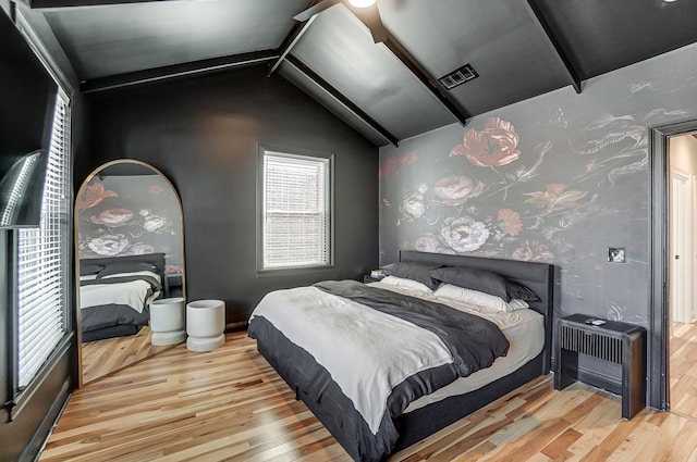 bedroom featuring vaulted ceiling with beams and light wood-type flooring