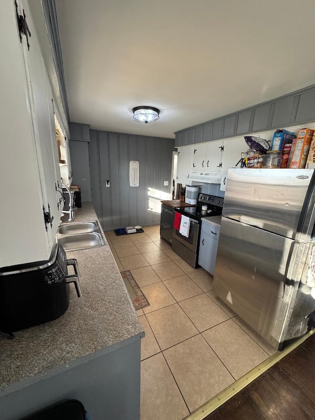 kitchen with stainless steel appliances, light tile patterned flooring, sink, and white cabinets