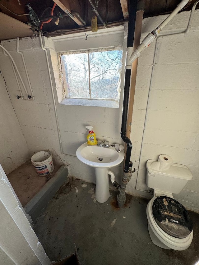 bathroom with toilet, sink, and concrete floors