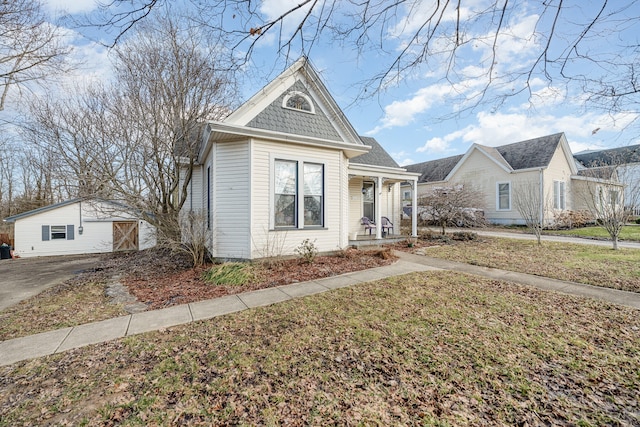 view of front of home with a garage, an outdoor structure, and a front lawn