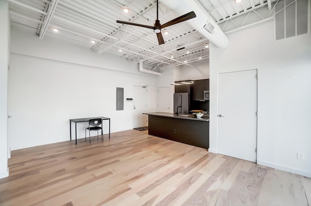 kitchen with electric panel, visible vents, a towering ceiling, appliances with stainless steel finishes, and light wood-type flooring