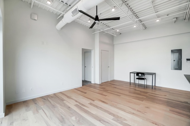 empty room featuring visible vents, a high ceiling, a ceiling fan, wood finished floors, and electric panel