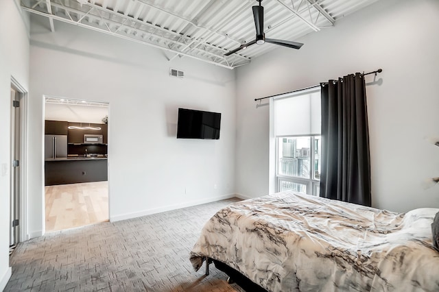 bedroom featuring visible vents, freestanding refrigerator, ceiling fan, wood finished floors, and baseboards