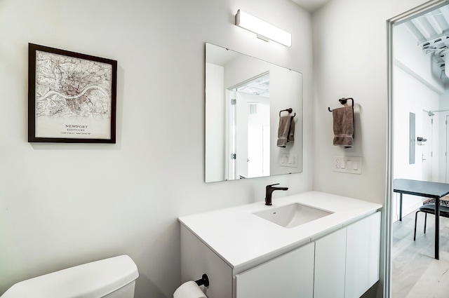 half bath featuring wood finished floors, vanity, and toilet