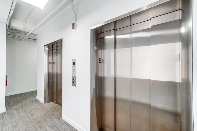 corridor featuring elevator and baseboards