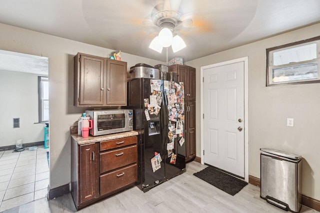 kitchen featuring dark brown cabinetry, light hardwood / wood-style flooring, and black fridge