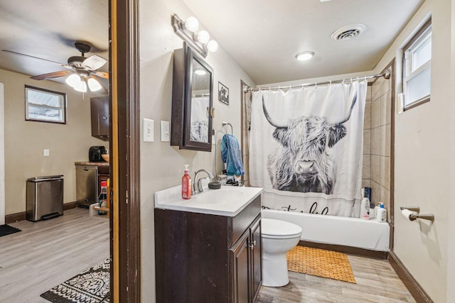 full bathroom featuring hardwood / wood-style flooring, ceiling fan, shower / bath combo, vanity, and toilet