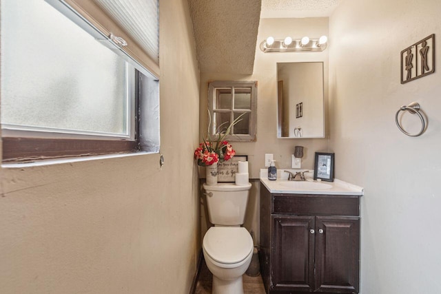 bathroom featuring vanity, a textured ceiling, and toilet