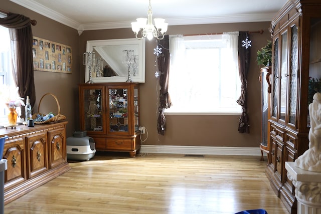 dining area featuring crown molding, a chandelier, and light hardwood / wood-style floors