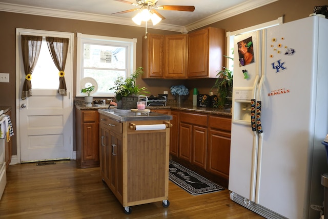 kitchen featuring a kitchen island, ornamental molding, white fridge with ice dispenser, ceiling fan, and dark wood-type flooring