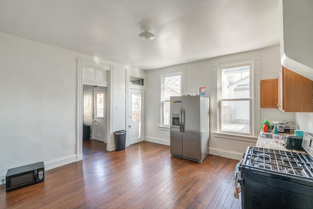 kitchen with dark wood-type flooring, gas range oven, and stainless steel fridge with ice dispenser