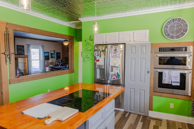 kitchen featuring butcher block countertops, white cabinetry, crown molding, hanging light fixtures, and stainless steel appliances