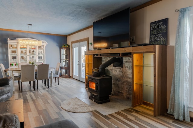 living room with french doors, hardwood / wood-style floors, a textured ceiling, and a wood stove