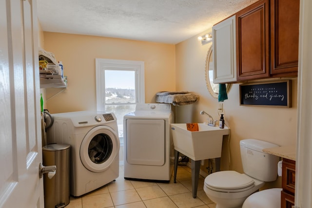 laundry room with light tile patterned flooring, washing machine and dryer, and a textured ceiling