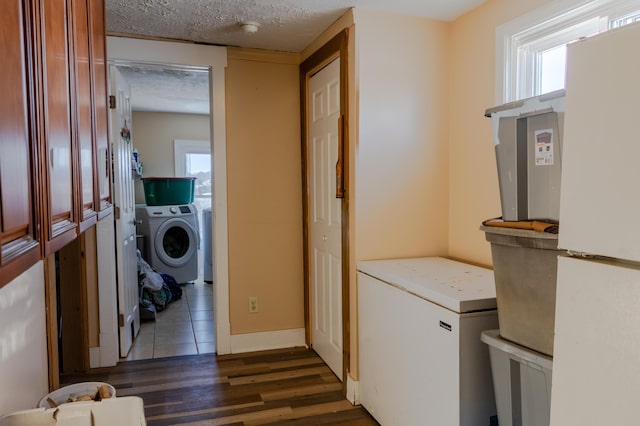 washroom featuring dark hardwood / wood-style flooring, washing machine and clothes dryer, and a textured ceiling