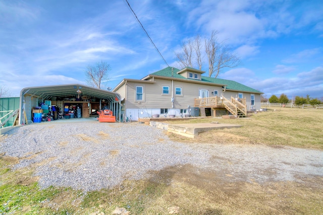 rear view of house with a carport, a yard, and a deck