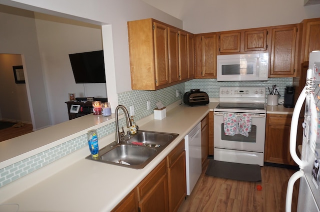 kitchen featuring hardwood / wood-style flooring, white appliances, sink, and backsplash