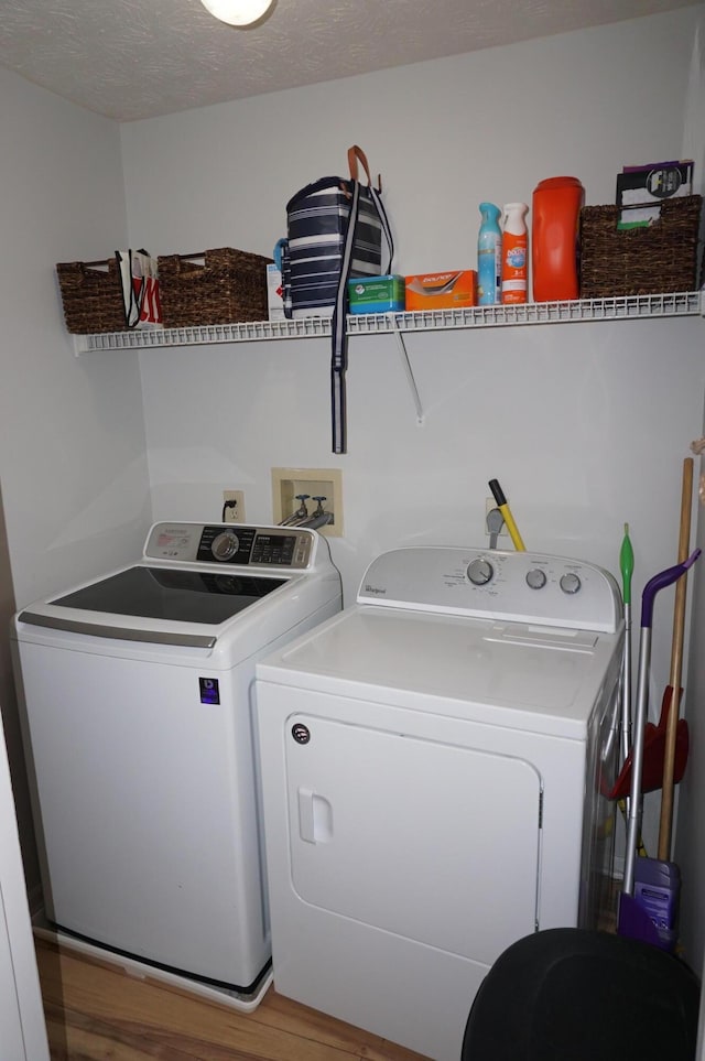 laundry area featuring wood-type flooring, washer and dryer, and a textured ceiling