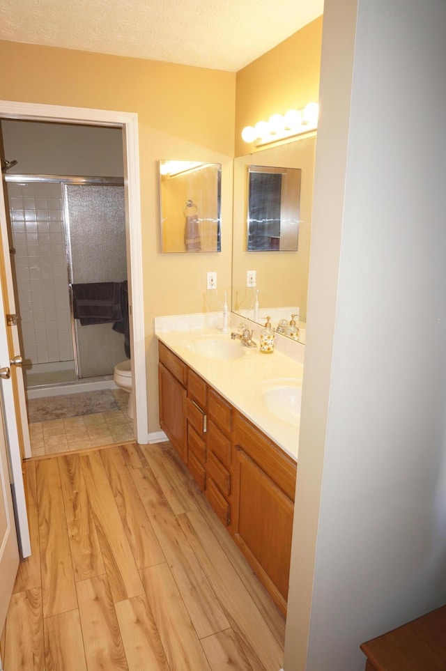 bathroom with an enclosed shower, vanity, hardwood / wood-style flooring, and toilet