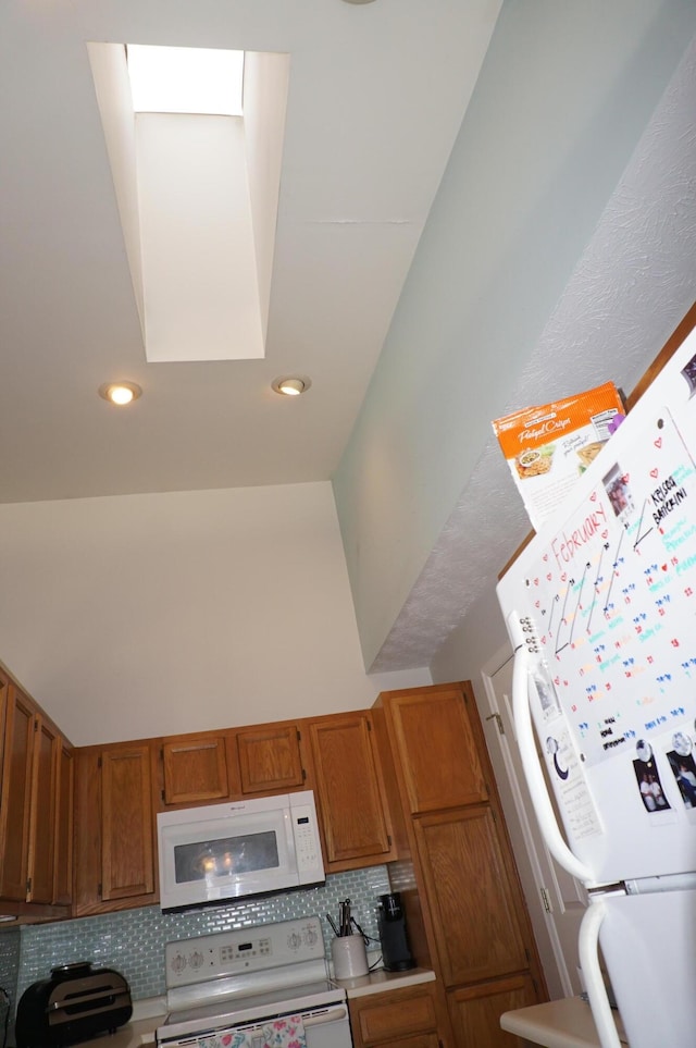 kitchen featuring white appliances, decorative backsplash, and a towering ceiling