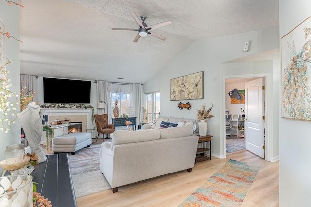 living room featuring ceiling fan, lofted ceiling, a textured ceiling, and light hardwood / wood-style floors