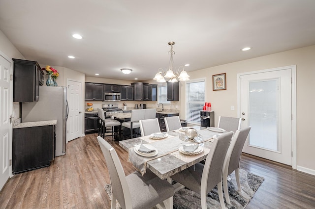 dining space with hardwood / wood-style flooring, sink, and a notable chandelier