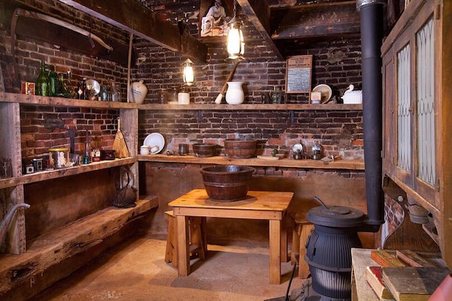 wine area with brick wall, a wood stove, and concrete floors