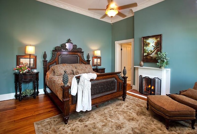 bedroom with wood-type flooring, ornamental molding, and ceiling fan