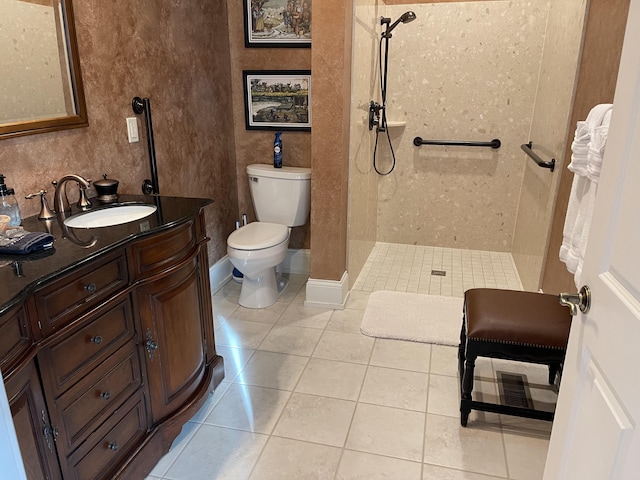 bathroom featuring tile patterned floors, toilet, vanity, and a tile shower