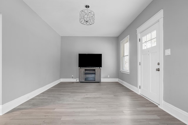 unfurnished living room with an inviting chandelier and light hardwood / wood-style flooring