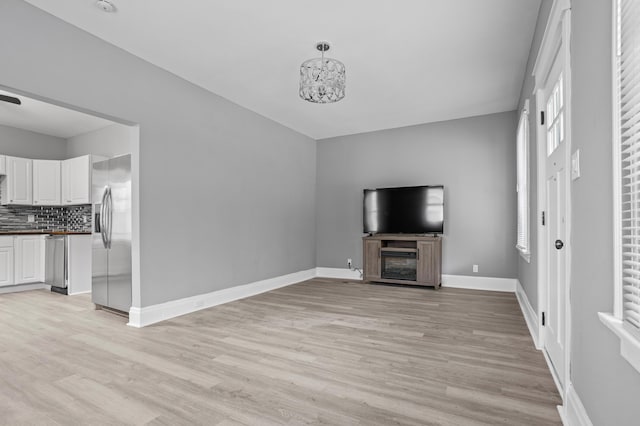 unfurnished living room with a notable chandelier and light hardwood / wood-style floors