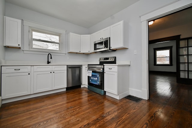 kitchen featuring white cabinets, appliances with stainless steel finishes, dark hardwood / wood-style flooring, and sink