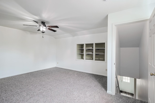 carpeted empty room with vaulted ceiling, built in features, and ceiling fan