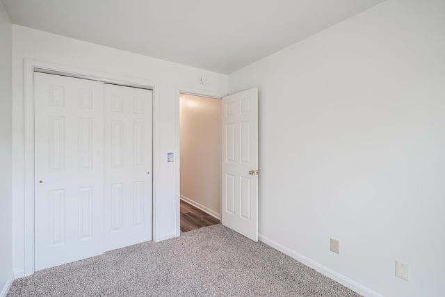 unfurnished bedroom with a closet and dark colored carpet