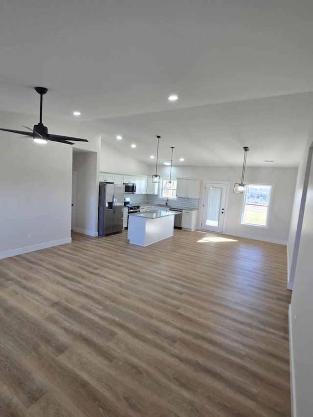 kitchen with pendant lighting, appliances with stainless steel finishes, white cabinetry, a kitchen island, and dark hardwood / wood-style flooring