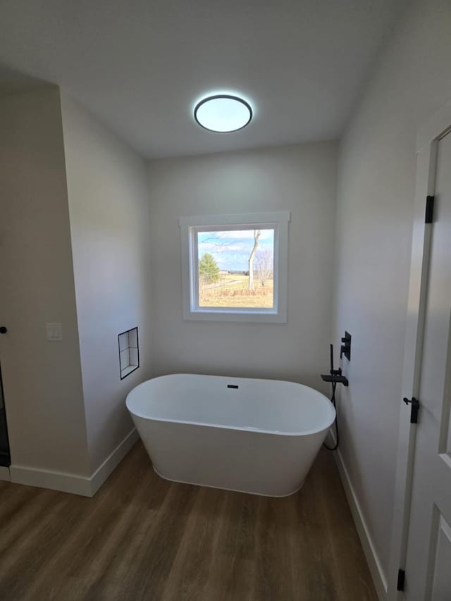 bathroom with a bath and hardwood / wood-style flooring