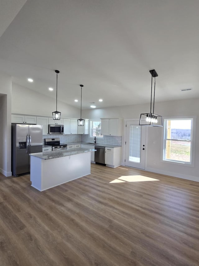 kitchen with hanging light fixtures, white cabinetry, appliances with stainless steel finishes, and decorative backsplash