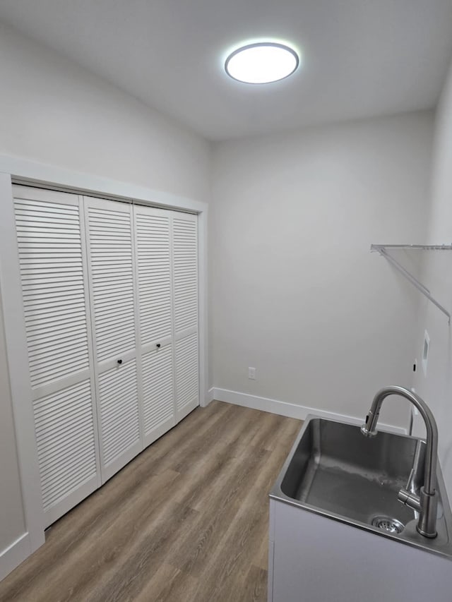 clothes washing area with sink and hardwood / wood-style floors