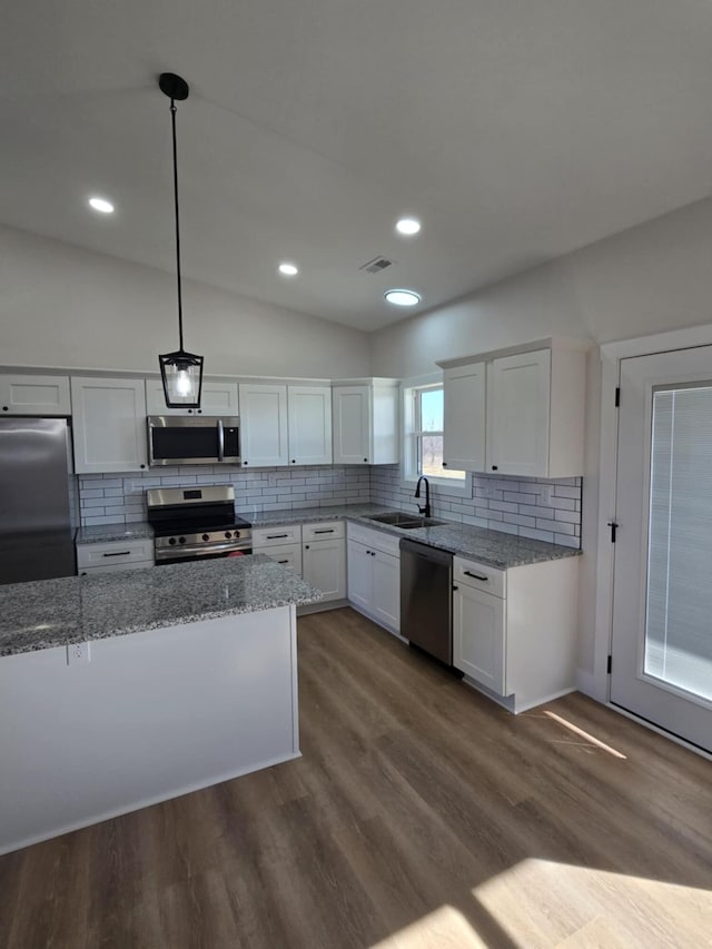 kitchen with light stone counters, hanging light fixtures, stainless steel appliances, and white cabinets