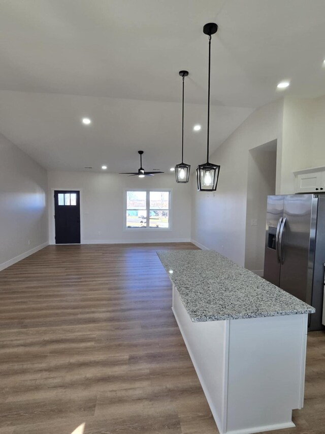 kitchen with hanging light fixtures, stainless steel refrigerator with ice dispenser, light stone counters, light hardwood / wood-style floors, and white cabinets