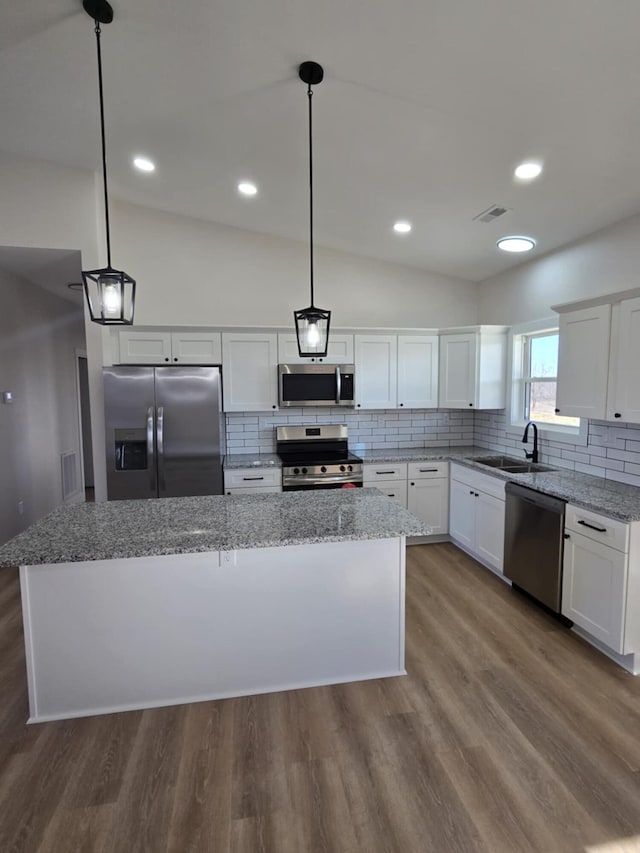 kitchen featuring a kitchen island, appliances with stainless steel finishes, pendant lighting, white cabinetry, and sink