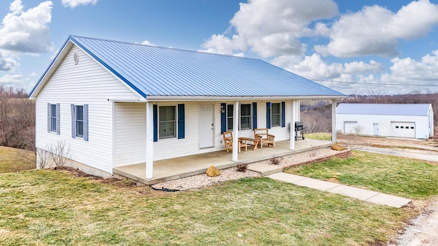 view of front of house featuring a porch, a garage, an outdoor structure, and a front lawn