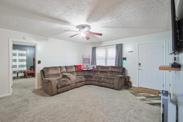 carpeted living room featuring ceiling fan and a textured ceiling