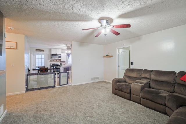 living room featuring ceiling fan, carpet flooring, and a textured ceiling