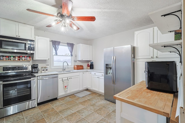 kitchen with sink, ceiling fan, appliances with stainless steel finishes, a textured ceiling, and white cabinets