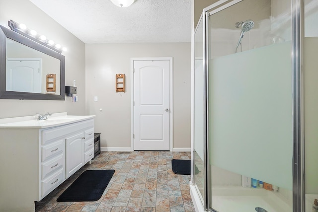 bathroom with a shower with door, vanity, and a textured ceiling