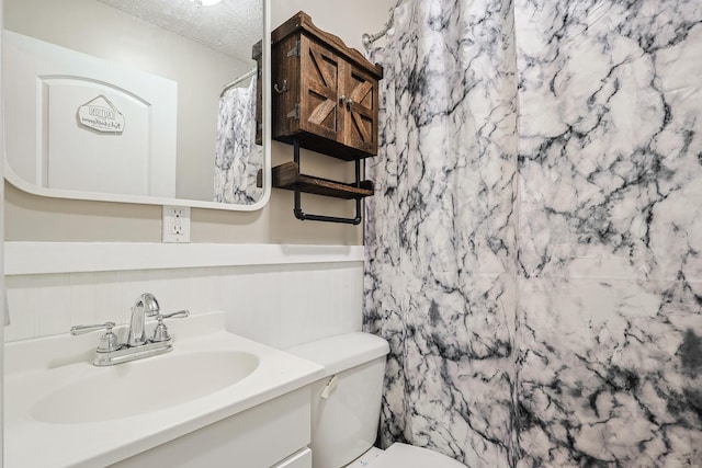 bathroom featuring a shower with curtain, vanity, toilet, and a textured ceiling